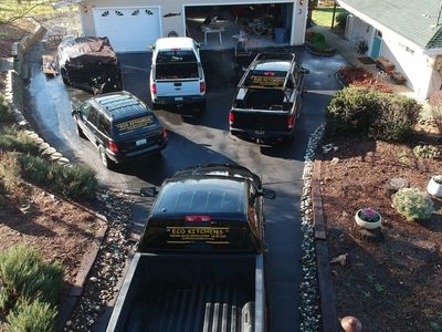 Four vehicles with Eco Kitchens branding parked in a driveway outside a garage.