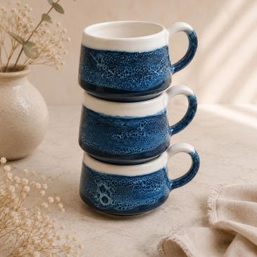 Stack of three blue and white ceramic mugs.