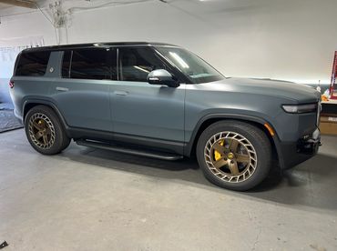 Matte gray electric SUV with bronze wheels parked indoors.