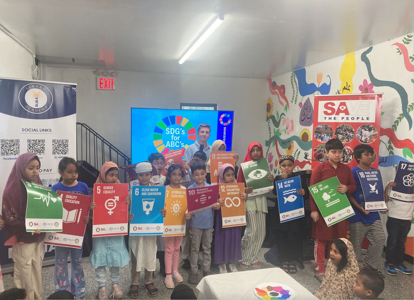 Children holding Sustainable Development Goals posters in a classroom setting.