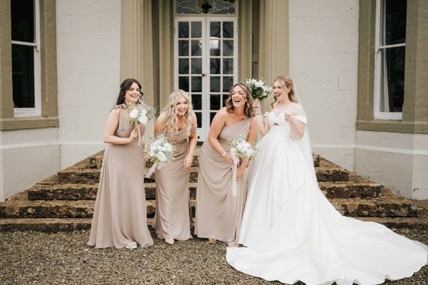 Bridal makeup on Bride and three Bridesmaids holding bouquets, laughing together