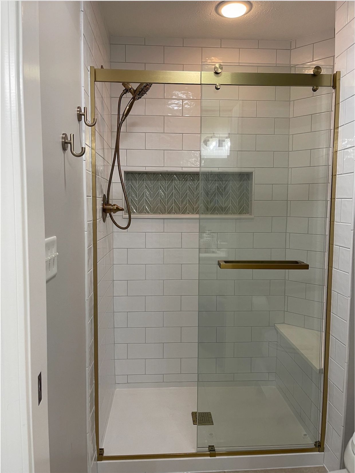 Modern shower with glass door and gold fixtures.
