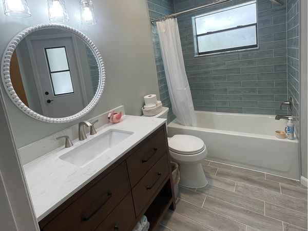 Modern bathroom with blue tiles and wooden vanity.