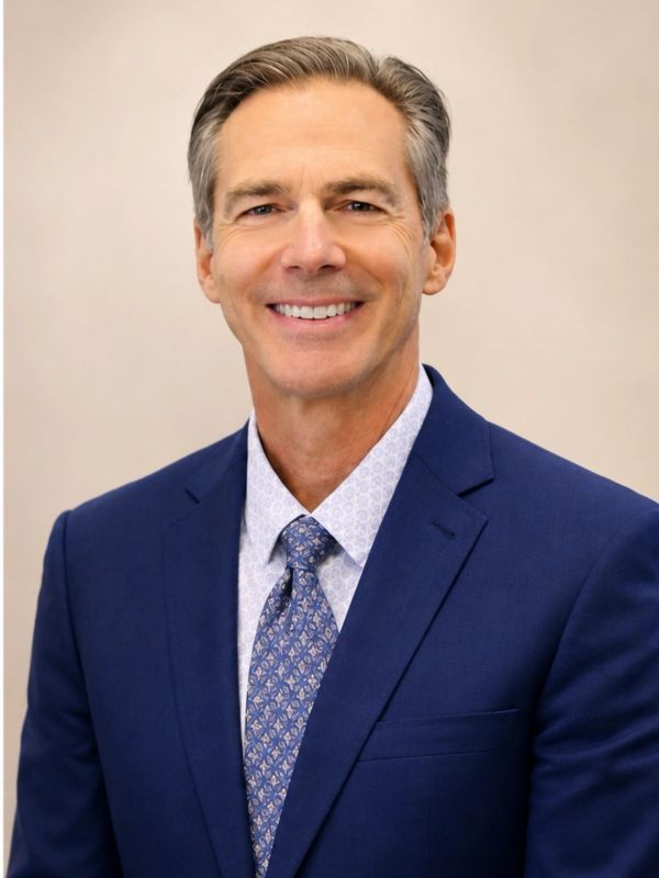 Smiling middle-aged man in blue suit and patterned tie.