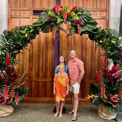 Family posing under a vibrant tropical floral arch indoors.