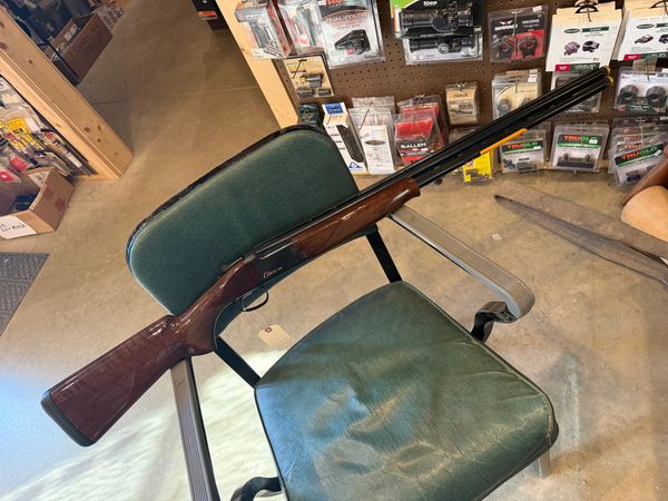 A shotgun resting on a green chair in a store.