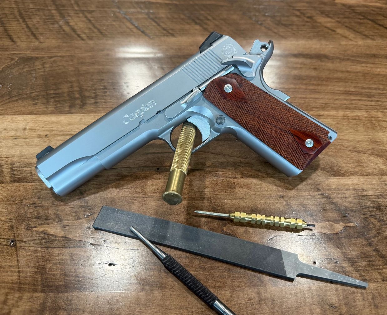 Silver Caspian handgun with wooden grips and gunsmithing tools.