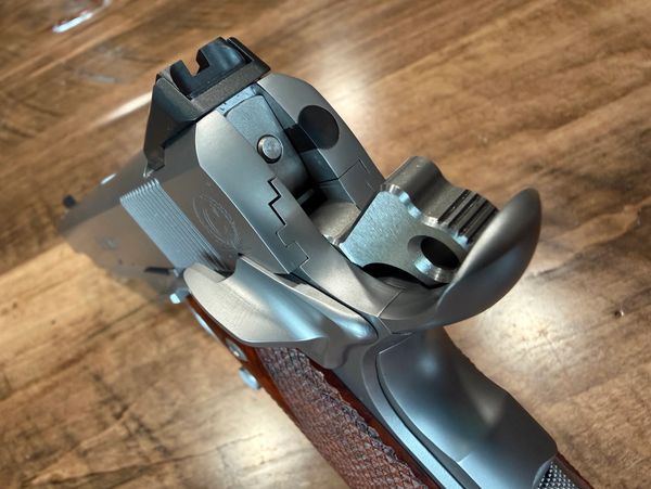 Close-up of a handgun's rear part on a wooden surface.
