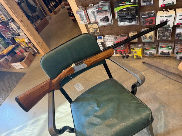 Shotgun resting on a green chair in a store.