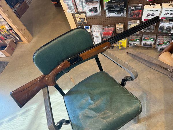 Shotgun resting on a green chair in a store.