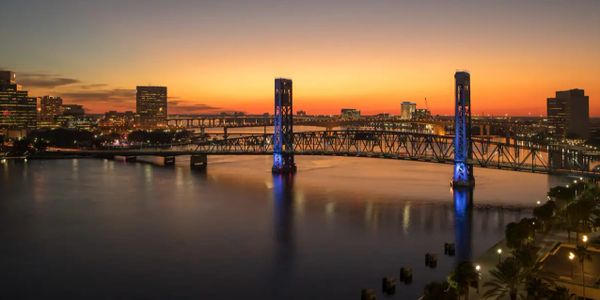 City bridge lit at twilight with a colorful sunset sky.