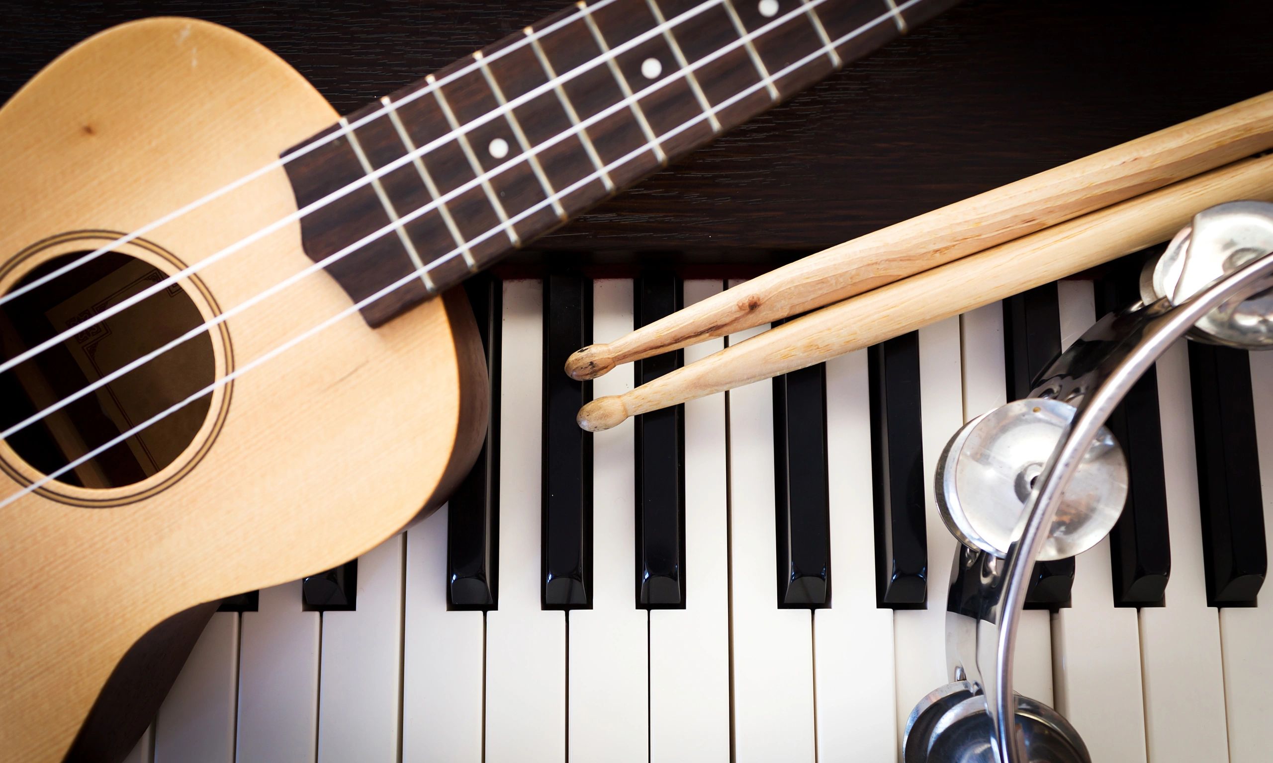 Ukulele, drum sticks, tambourine, and piano keyboard