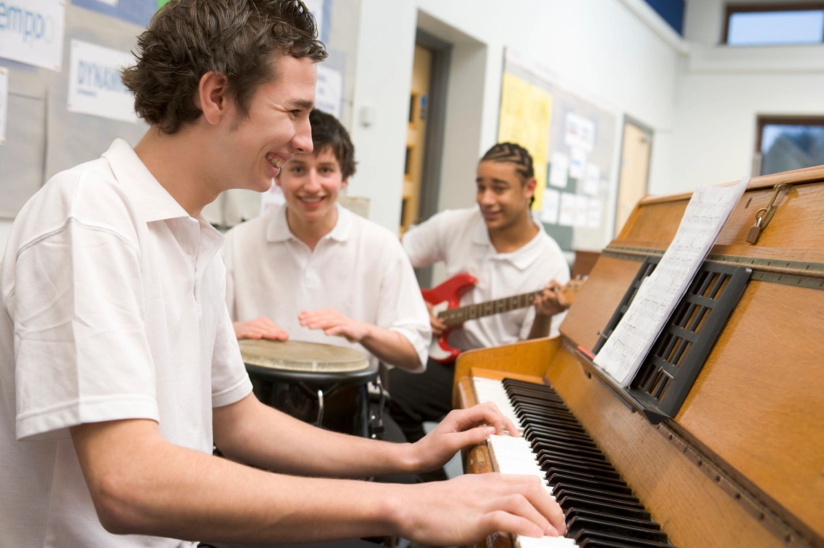 Three highschool boys playing instruments in a classroom.