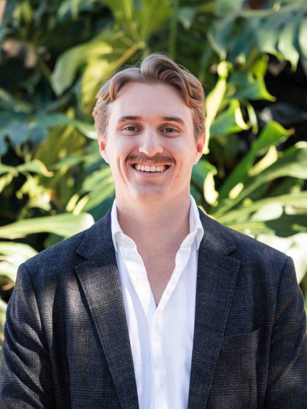 Smiling man in a blazer with lush greenery background