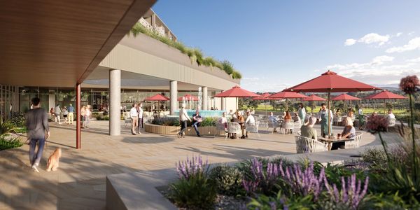 Outdoor patio area with people relaxing under red umbrellas.
