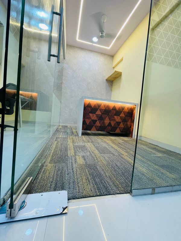 Modern office room with glass doors and geometric wooden desk.