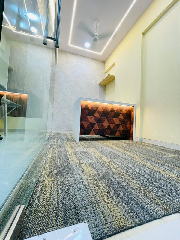 Modern office with geometric wooden desk and LED ceiling lights.