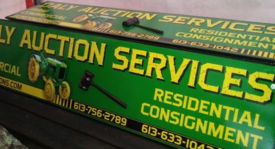 Green and yellow auction services sign with contact numbers.
