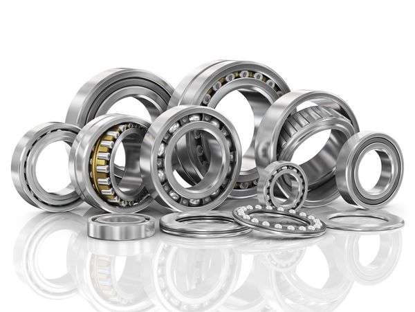 Various types of shiny metal ball bearings arranged on a reflective surface.