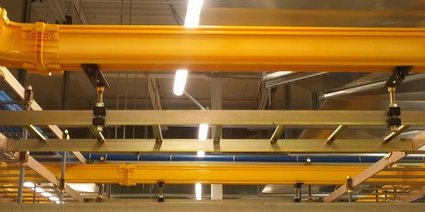 Yellow industrial pipes and ceiling lights in a warehouse.