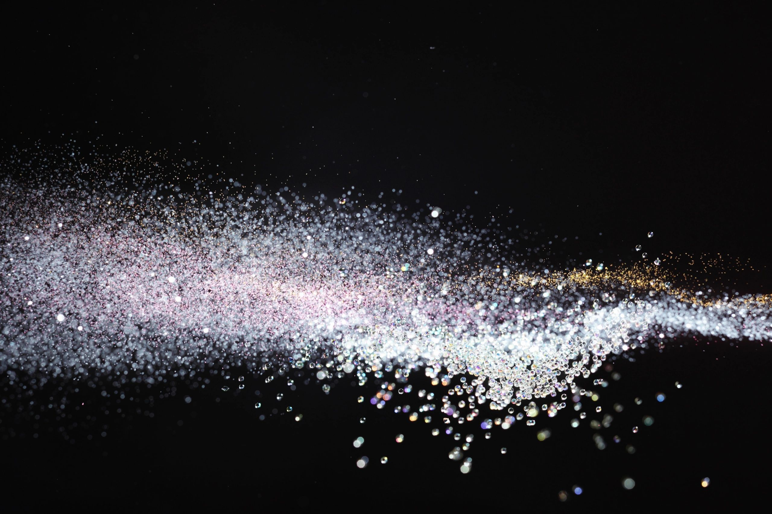 Particles of glitter and light suspended in dark space.