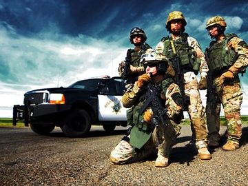 Four SWAT Officers in tactical gear communicating on headset, in front of Ford Highway Patrol Truck 