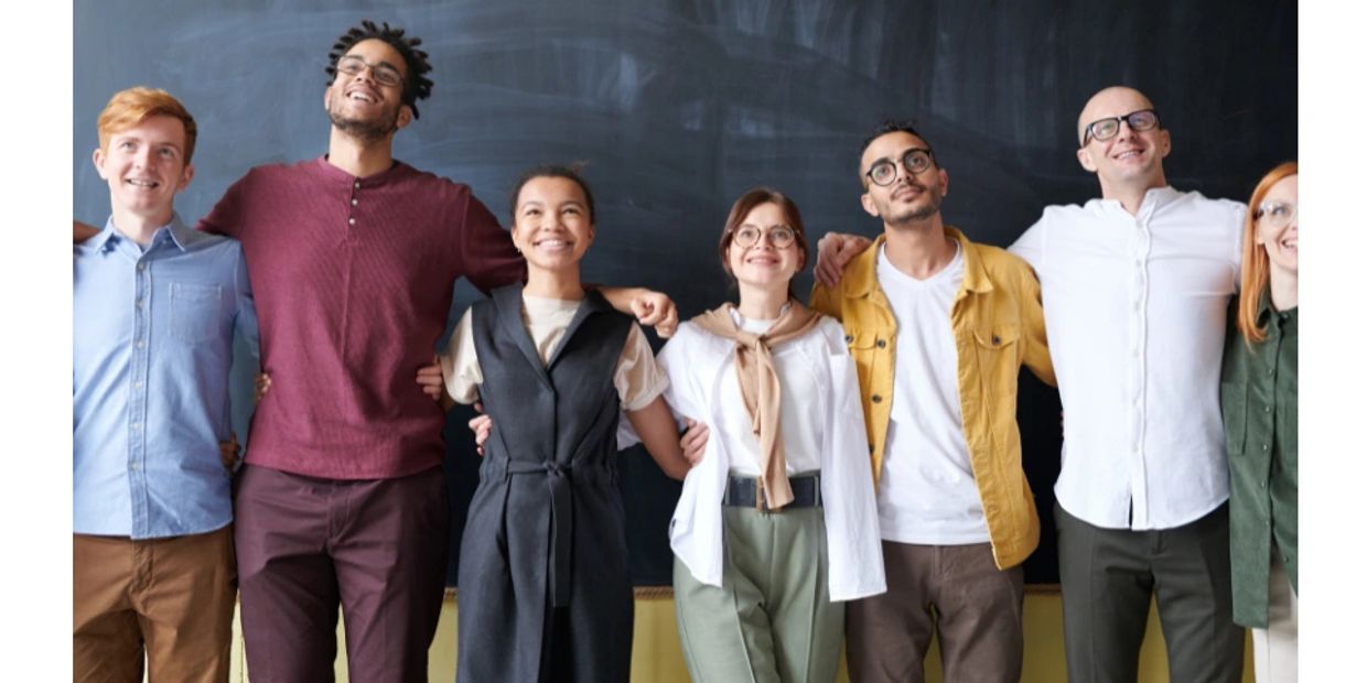 A diverse group of friends standing arm in arm smiling.