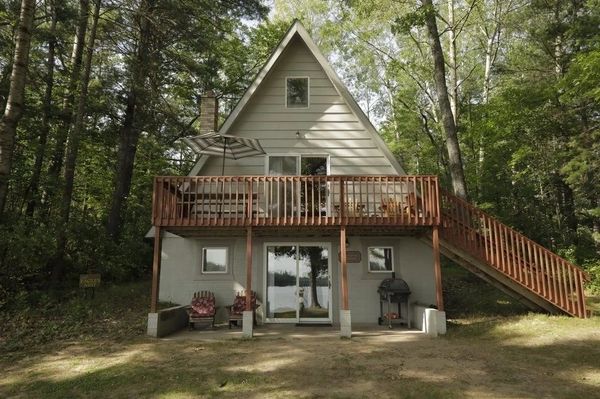 A-frame cabin by lake and trees.
