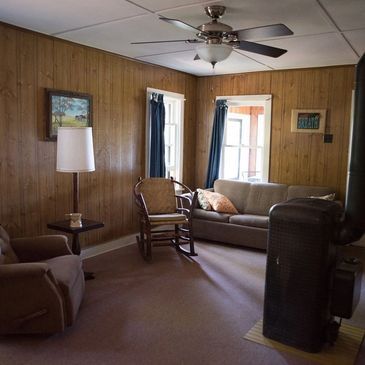Wood-paneled living room with a sofa and stove