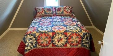 Loft bedroom with colorful quilt.