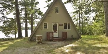 A-frame cabin by lake and trees.