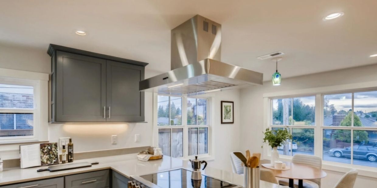 Modern kitchen with gray cabinets, stainless steel appliances, and a cozy dining area by large windows.