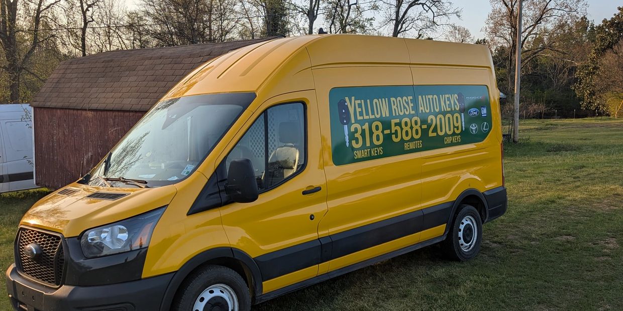Yellow van with Yellow Rose Auto Keys advertisement parked on a driveway.
