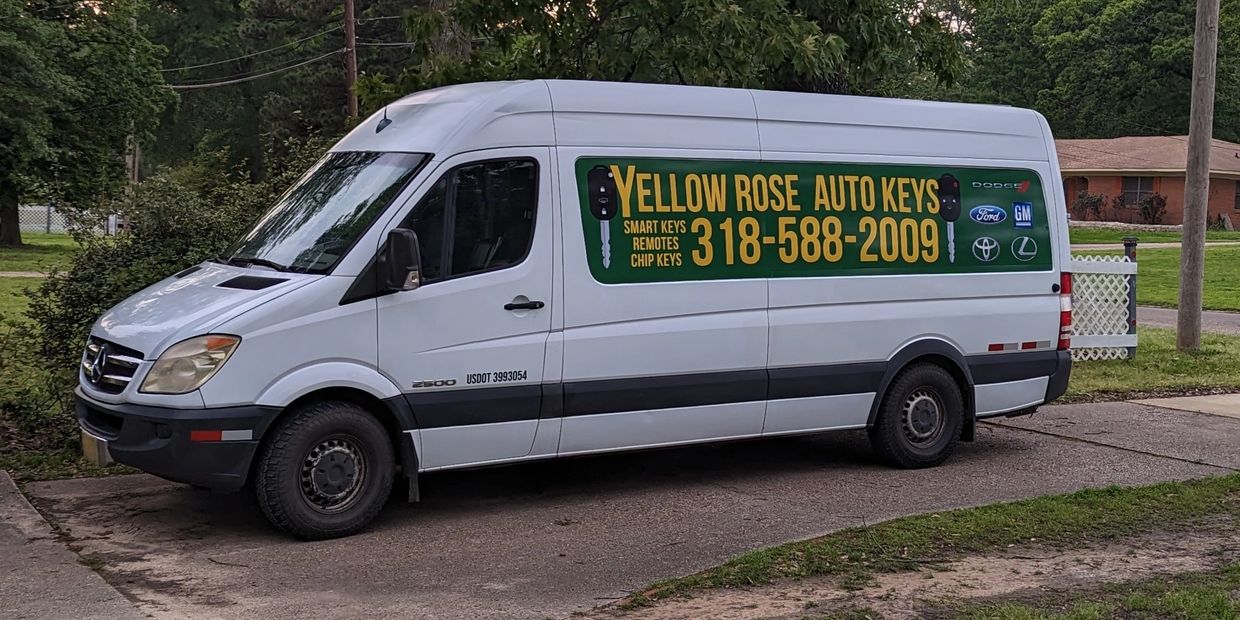 White van with Yellow Rose Auto Keys advertisement parked on a driveway.