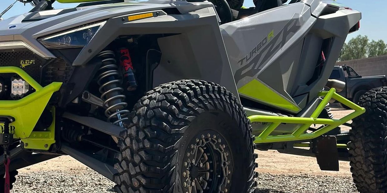 Off-road vehicle with rugged tires and bright green frame on rocky terrain.
