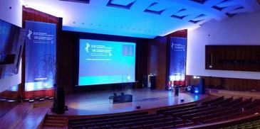 Empty auditorium with stage and large screen displaying a presentation.