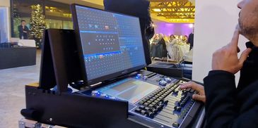 Person operating a professional lighting control console at an event.