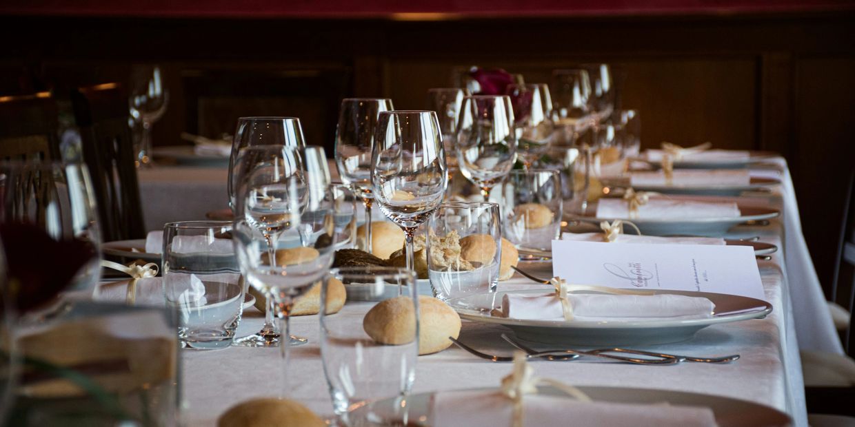Elegantly set dining table with glasses and bread rolls.