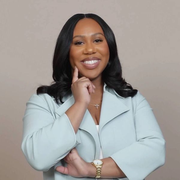 Confident woman in light blue blazer smiling warmly at the camera.