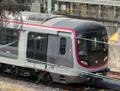 Modern commuter train on railway tracks in an urban setting.