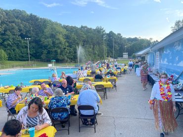 People eating at tables around the Karns Pool for the annual Luau fundraiser