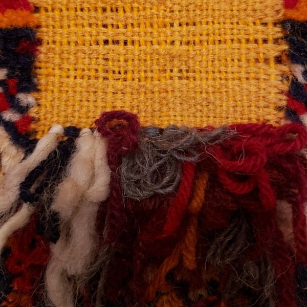 Close-up of a colorful woven textile with fringes.