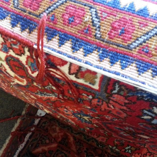 Close-up of a colorful, patterned woven rug with red threads.