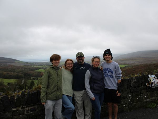 Family posing together on a cloudy day with scenic countryside.