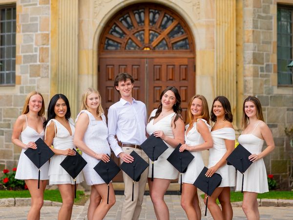 Group of graduates posing with caps in front of a building.