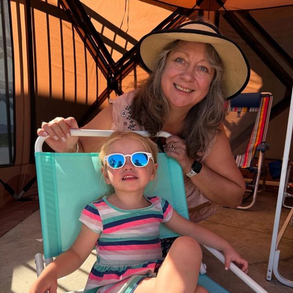 Smiling woman with child in sunglasses relaxing in a tent.