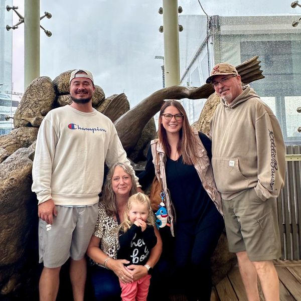 Family photo with five people smiling in front of a sculpture.