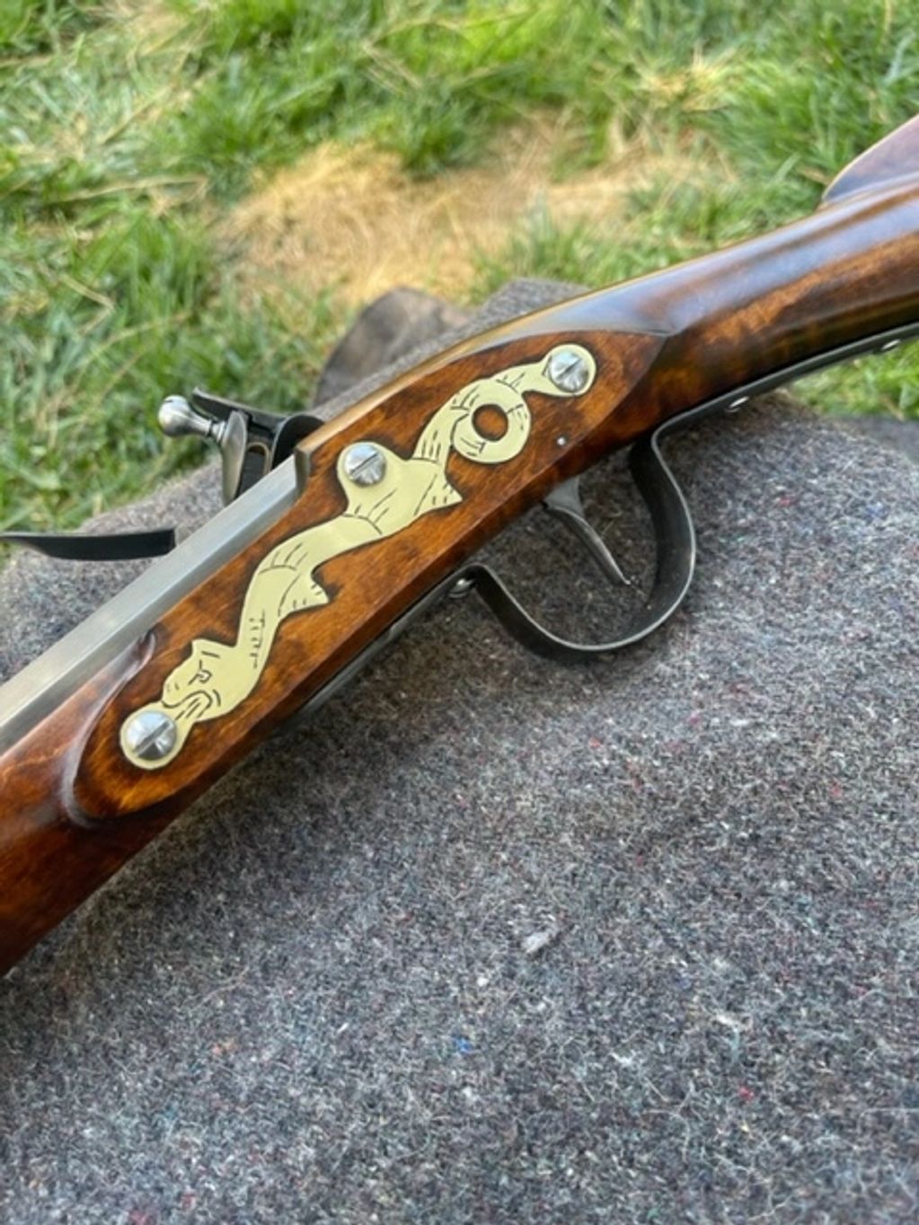 Close-up of an antique rifle with ornate brass detailing on the wooden stock.