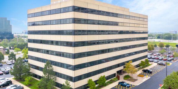 Modern office building with striped windows and surrounding parking lot.