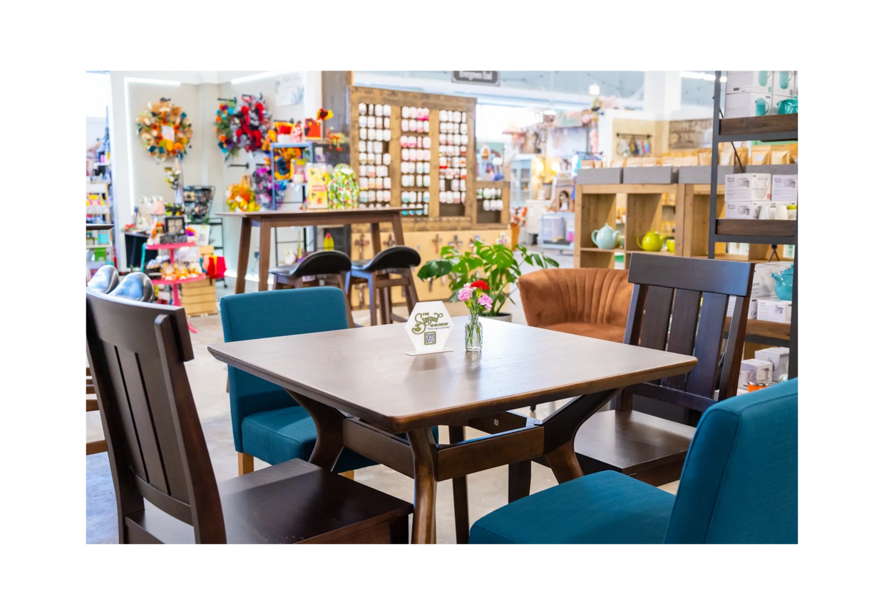 Tea lounge setting with tables, chairs with a Steeped Leaf Logo sign on the table and fresh flowers.